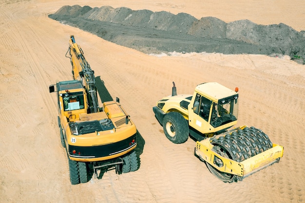 La excavadora limpia el sitio de construcción compactando la tierra con un apisonador especial.