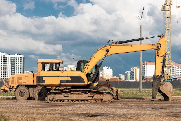 La excavadora y la motoniveladora se encuentran una al lado de la otra contra el cielo azul. Equipo de movimiento de tierras de construcción pesada. Construcción de carreteras y comunicaciones subterráneas. Industria de construccion.