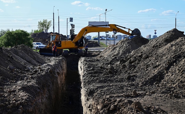 Excavadora durante el movimiento de tierras a cielo abierto sobre fondo de cielo azul Maquinaria de construcción y equipo pesado de movimiento de tierras para excavación, carga, elevación y transporte de carga en los sitios de trabajo