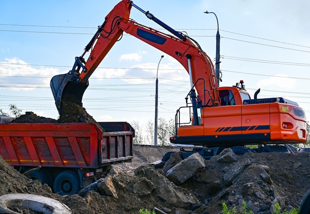 Excavadora durante el movimiento de tierras a cielo abierto sobre fondo de cielo azul Maquinaria de construcción y equipo pesado de movimiento de tierras para excavación, carga, elevación y transporte de carga en los sitios de trabajo