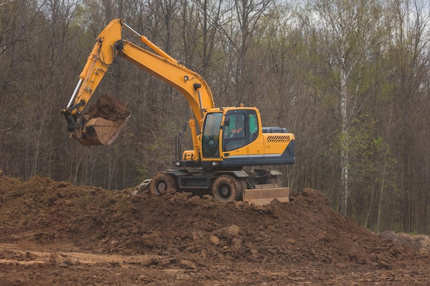 Excavadora naranja en el trabajo: construcción de carreteras para una nueva autopista, telefoto