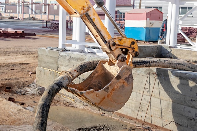 Una excavadora o cargadora ayuda en la producción de trabajos monolíticos de hormigón armado en un sitio de construcción Uso de equipos de construcción