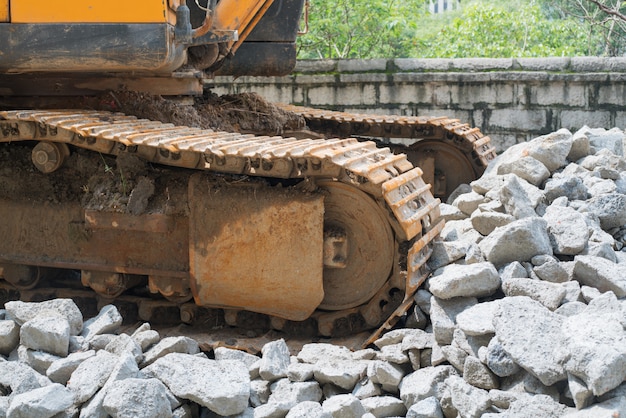 Excavadora de organge pesada con pala de pie en la colina con rocas