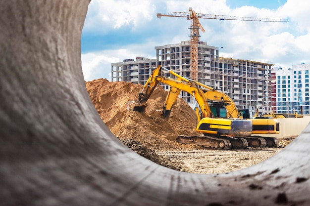 Foto excavadora pesada en el sitio de construcción vista de la excavadora a través de la tubería de hierro equipos de construcción para movimiento de tierras excavadora de cantera