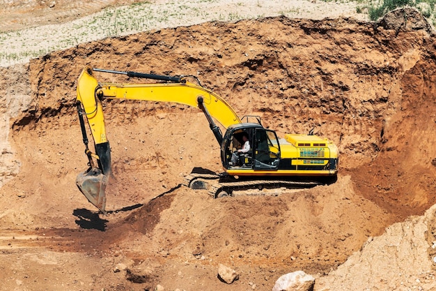 Una excavadora en un pozo de arena carga un camión volquete con arena Extracción de arena en un pozo abierto materiales de construcción naturales