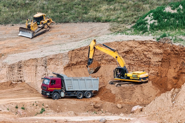 Una excavadora en un pozo de arena carga un camión volquete con arena Extracción de arena en un pozo abierto materiales de construcción naturales