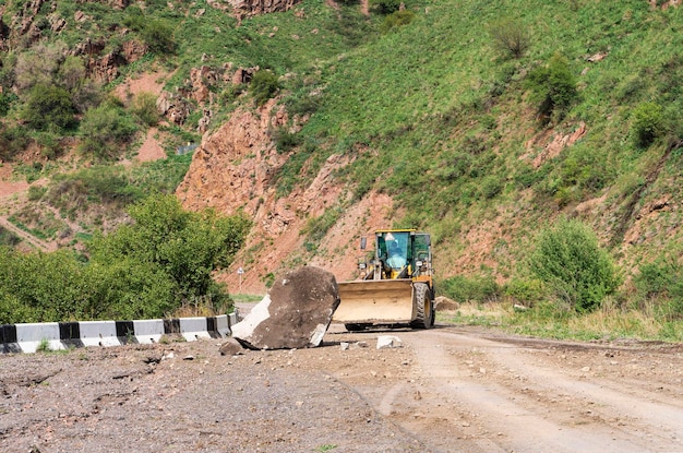 Excavadora quitando rocas de una carretera de montaña después de un deslizamiento de tierra