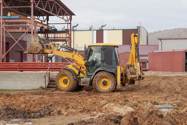 La excavadora rellena el foso con el cucharón delantero Mueve la tierra alrededor del sitio de construcción Primer plano Equipo de construcción pesado