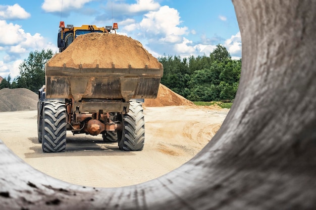 La excavadora rellena el foso con el cucharón delantero Mueve la tierra alrededor del sitio de construcción Primer plano Equipo de construcción pesado