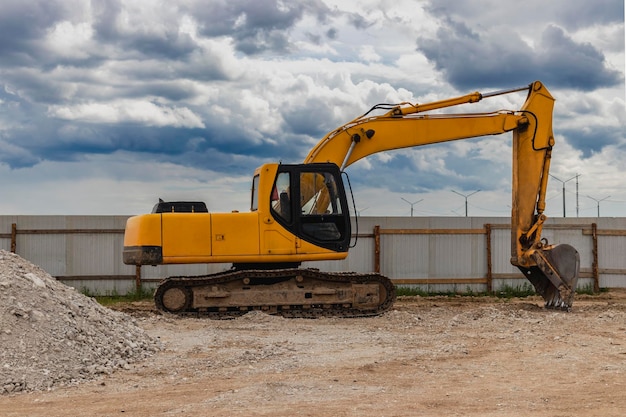 Excavadora retroiluminada en un sitio industrial contra el fondo del cielo nocturno Maquinaria de construcción para movimiento de tierras