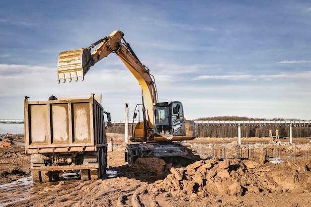 Una excavadora de ruedas carga un camión volquete con tierra y arena La excavadora excava el suelo en el sitio de construcción Remoción de suelo de un sitio de construcción o cantera