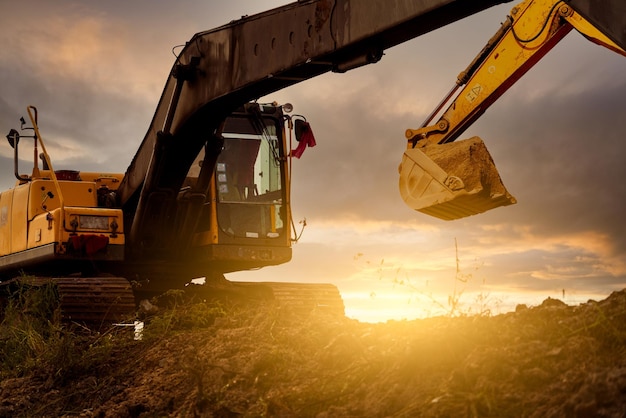 Excavadora en el sitio de construcción excavando el suelo con un cubo de excavadora excavador en la excavador del cielo al atardecer