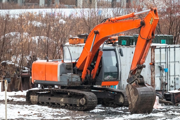 Excavadora sobre orugas naranja en un sitio de construcción en invierno