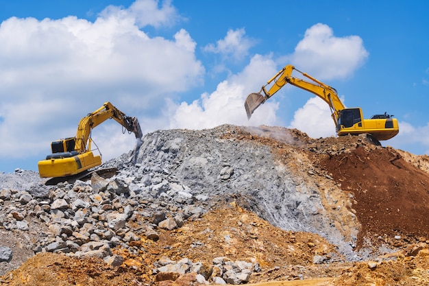 Excavadoras y trituradoras de piedra de la minería bajo un cielo azul con nubes