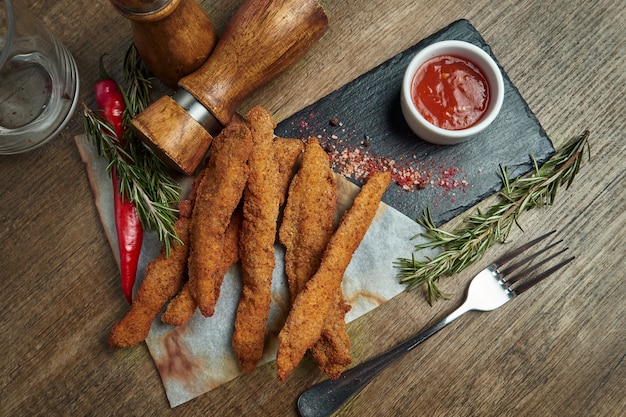 Un excelente aperitivo de cerveza es un conjunto de nuggets de pollo, papas fritas con salsa de pergamino en una bandeja de piedra. Comida de pub. Vista superior