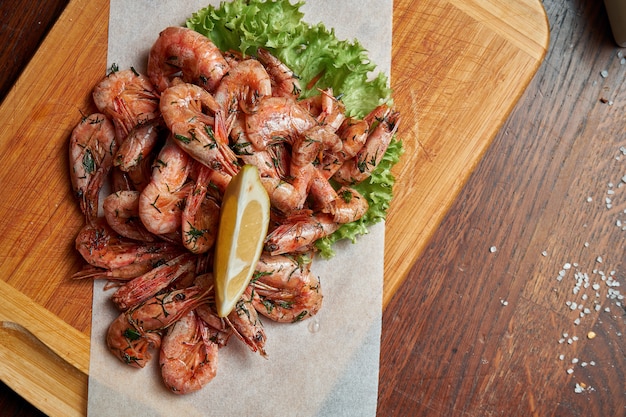 Un excelente aperitivo de cerveza es un conjunto de pequeñas papas fritas de camarones en pergamino en una bandeja de madera. Comida de pub. Cerrar mariscos