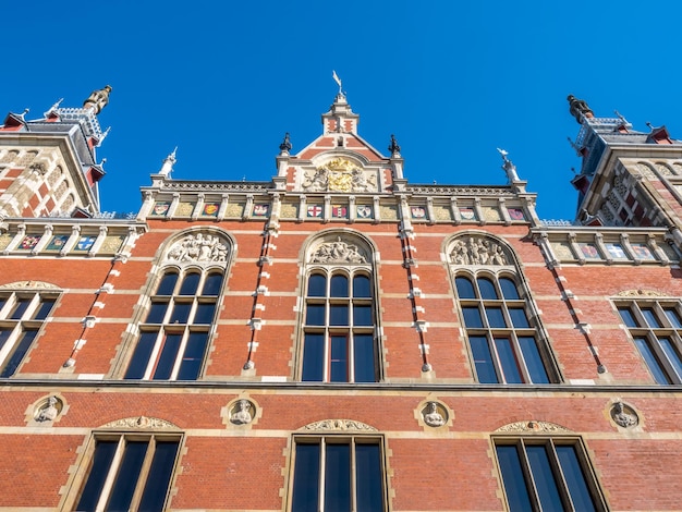 Excelente arquitetura bonita do edifício da estação de trem de Amsterdã sob o céu azul, Holanda