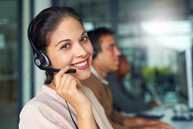 Foto excelente atendimento ao cliente vai longe retrato de um agente de call center trabalhando em um escritório com seus colegas em segundo plano