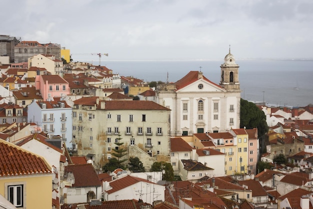 Excelentes vistas do bairro de alfama com o mar ao fundo em um dia nublado em lisboa. casas coloridas