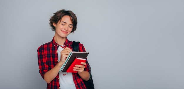 Foto excepcional y desarrollado inteligente joven estudiante universitario con mochila pluma y cuadernos en las manos escribiendo horario de clase universidad estudio escuela educación clases universitarias aprender conocimiento