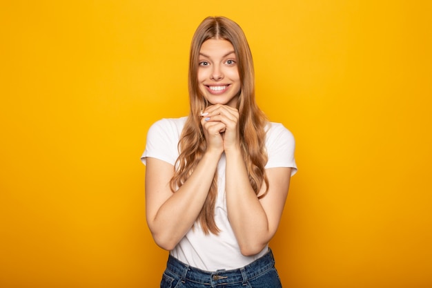 excitada chica rubia sonriente con el pelo largo aislado en amarillo