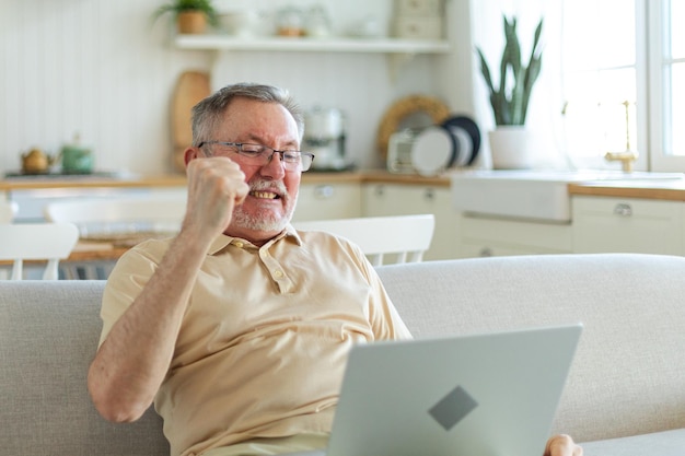 Excitado hombre de mediana edad eufórico ganador abuelo más viejo maduro mirando la computadora portátil leyendo