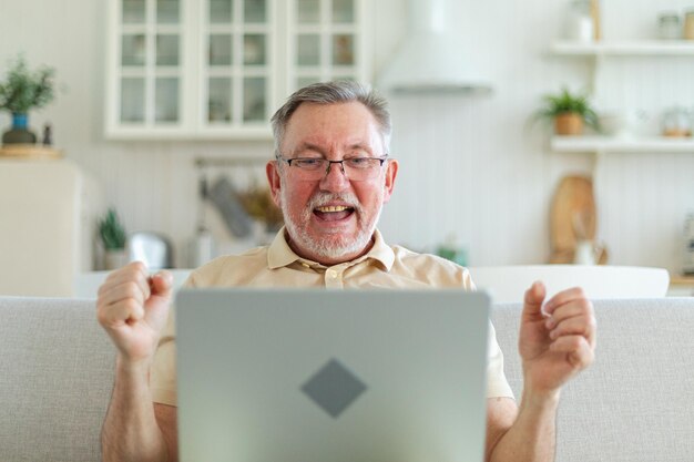 Excitado homem sênior de meia-idade, vencedor eufórico, avô maduro mais velho olhando para laptop lendo gr