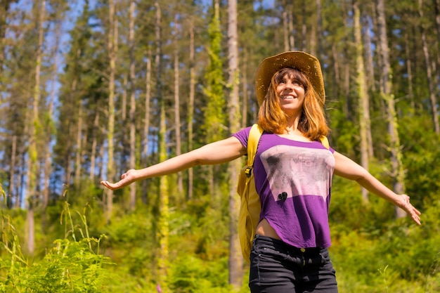 Un excursionista aventurero muy feliz junto a unos pinos en el bosque