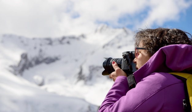 Excursionista con cámara y mochila tomando foto de hermosa montaña