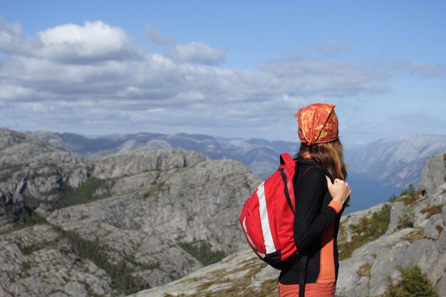 Excursionista chica de pie sobre una roca y mirando las montañas