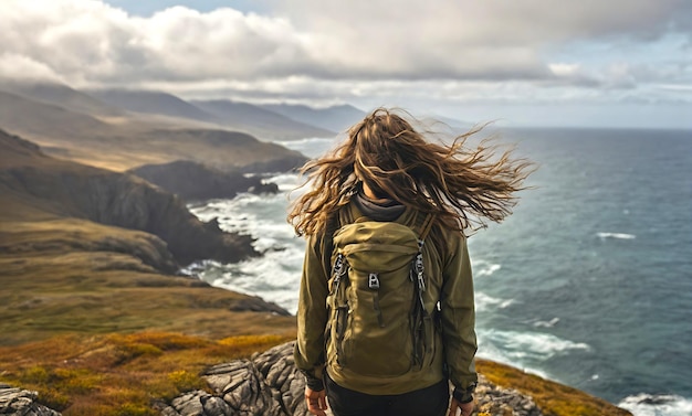 Un excursionista se detiene en un acantilado el viento azotando a través de su cabello como el paisaje impresionante