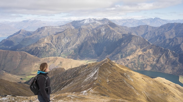 Una excursionista disfruta de las hermosas vistas del paisaje alpino desde la cumbre de la montaña de Nueva Zelanda