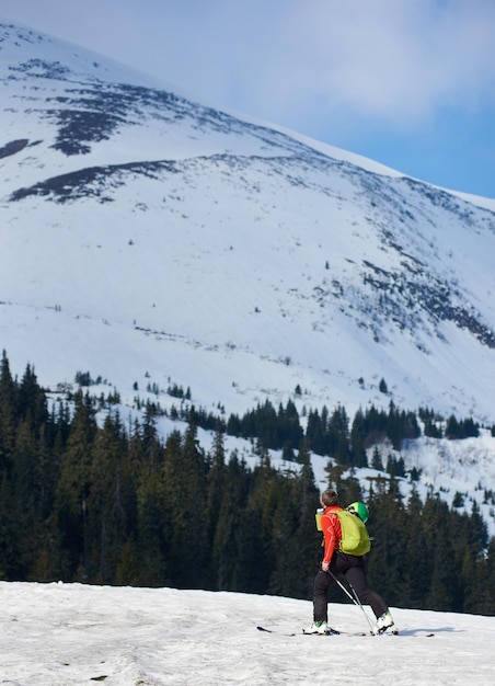 Excursionista esquiador con mochila sobre esquís en nieve blanca y profunda sobre el fondo de un hermoso paisaje invernal
