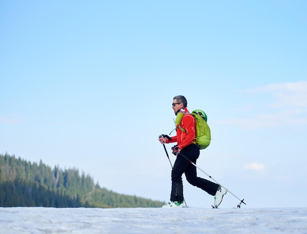 Excursionista esquiador con mochila sobre esquís en nieve blanca y profunda sobre el fondo de un hermoso paisaje invernal