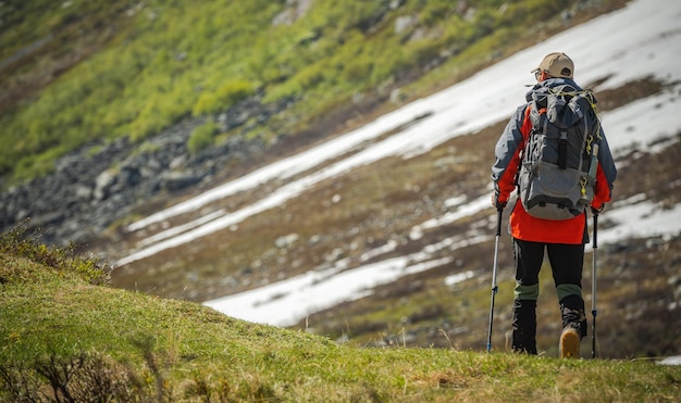 Excursionista experimentado con mochila y bastones de trekking en senderos de montaña