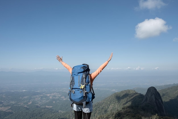 Un excursionista extiende sus brazos sobre la cima de la montaña.