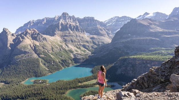 Excursionista femenina disfrutando de hermosas vistas sobre el valle alpino con lagos glaciares rodeados de montañas