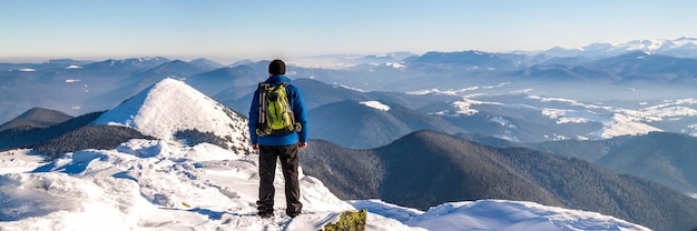 Excursionista de hombre en la cima de una montaña en invierno