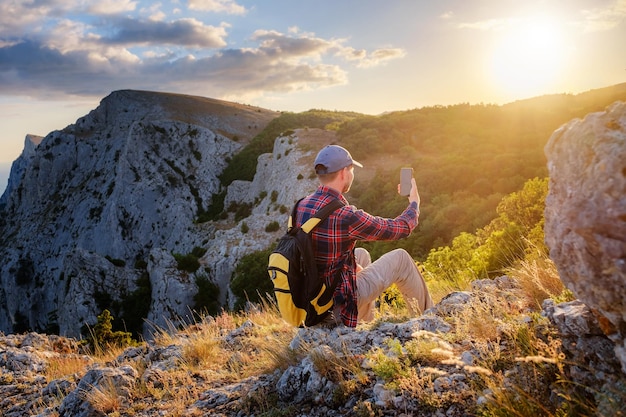 Excursionista de hombre fuerte tomando fotos con un teléfono inteligente en el pico de la montaña