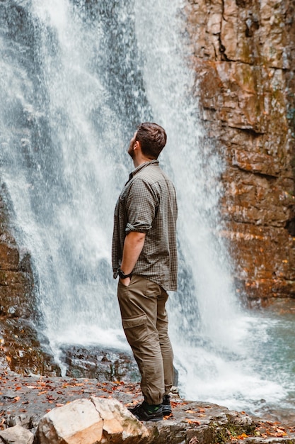 Excursionista joven fuerte mirando el espacio de copia de cascada