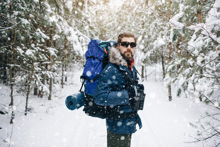 Excursionista masculino en un camino cubierto de nieve del bosque de invierno