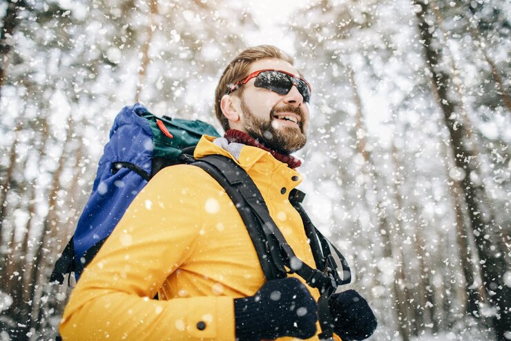 Excursionista masculino feliz atravesando nevadas en el bosque