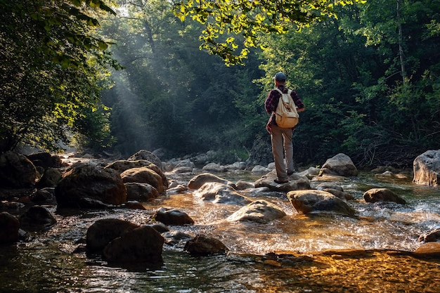 Excursionista masculino feliz trekking al aire libre en el bosque cerca del río