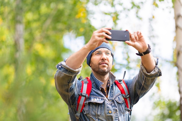 Excursionista de mediana edad tomando una foto con su teléfono móvil