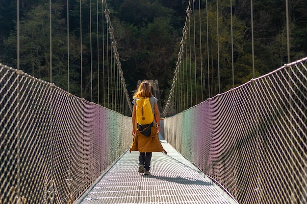 Foto un excursionista con mochila amarilla cruzando el puente colgante de holtzarte, larrau. en el bosque o jungla de irati, pirineos atlánticos de francia