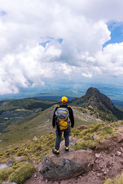 Un excursionista con una mochila de pie en la cima de la montaña.