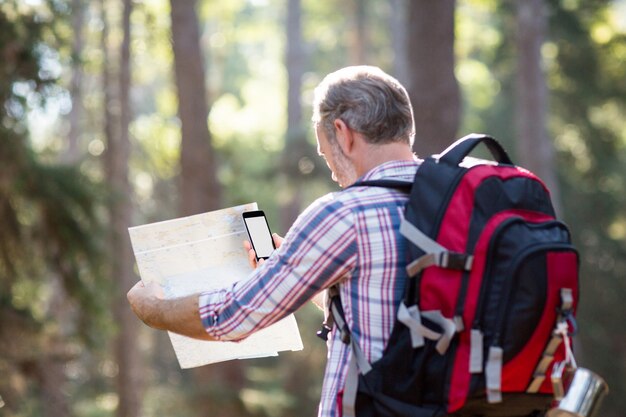 Excursionista con mochila con teléfono móvil y mapa