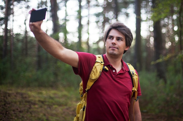 Excursionista con mochila tomando selfie en el bosque