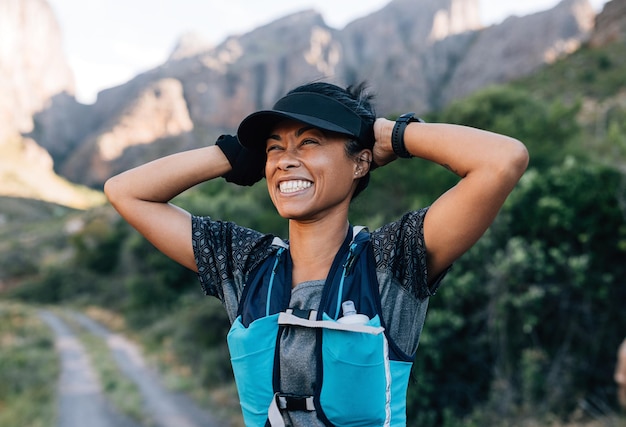 Excursionista de mujer riendo sosteniendo gorra disfrutando de la vista Mujer joven en ropa deportiva en terreno salvajex9xA