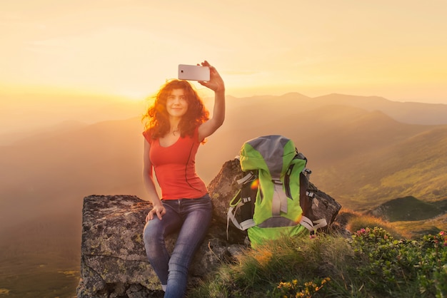 Excursionista de mujer tomando la foto en el pico de la montaña